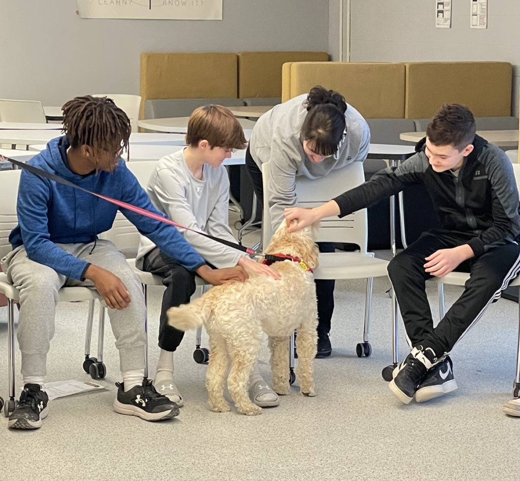 Four students petting a dog.